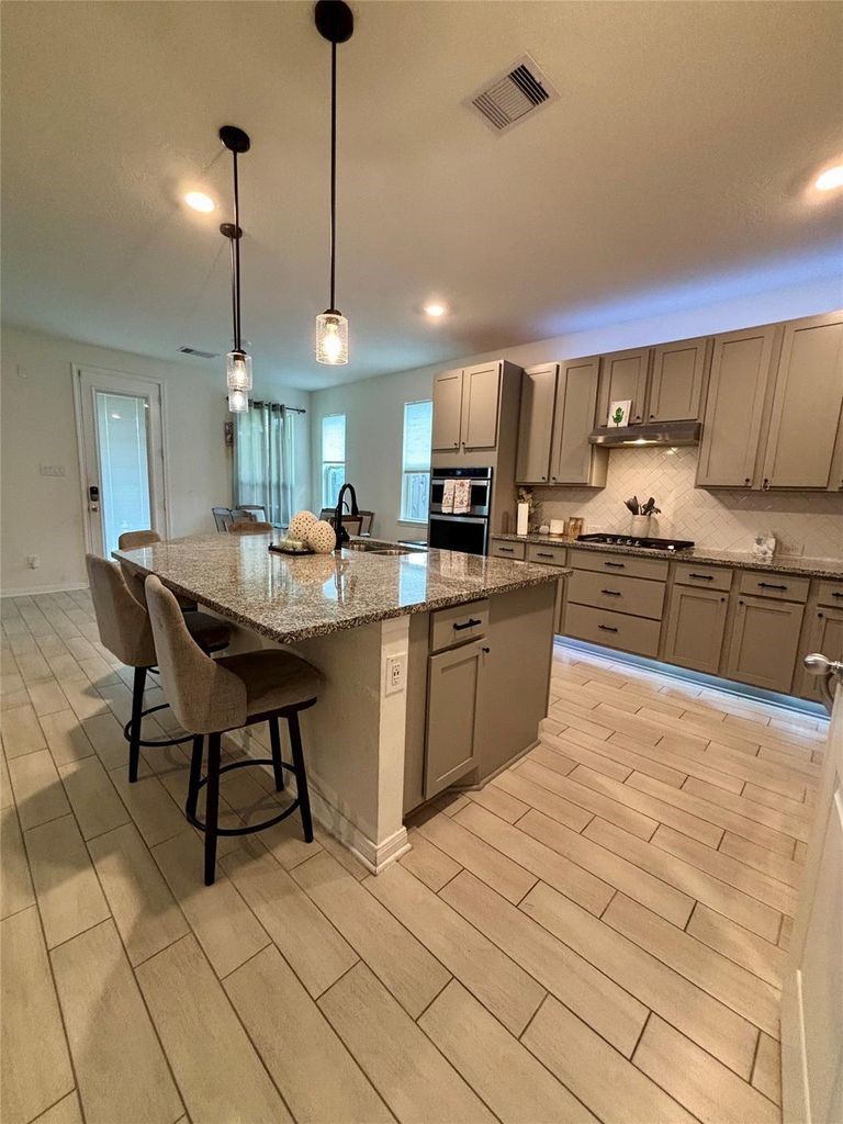 734 Hardwood Grv Court Houston, TX 77090 - Photo 8 of 23 a kitchen with stainless steel appliances kitchen island granite countertop a sink a stove a dining table and chairs