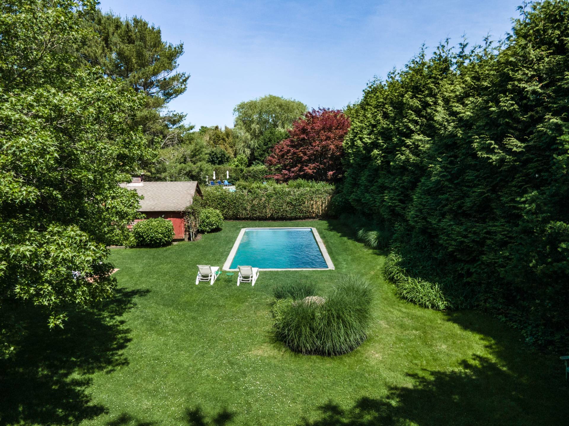 53 Hildreth Lane Bridgehampton, NY 11932 - Photo 7 of 37 a view of a backyard with lawn chairs under an umbrella