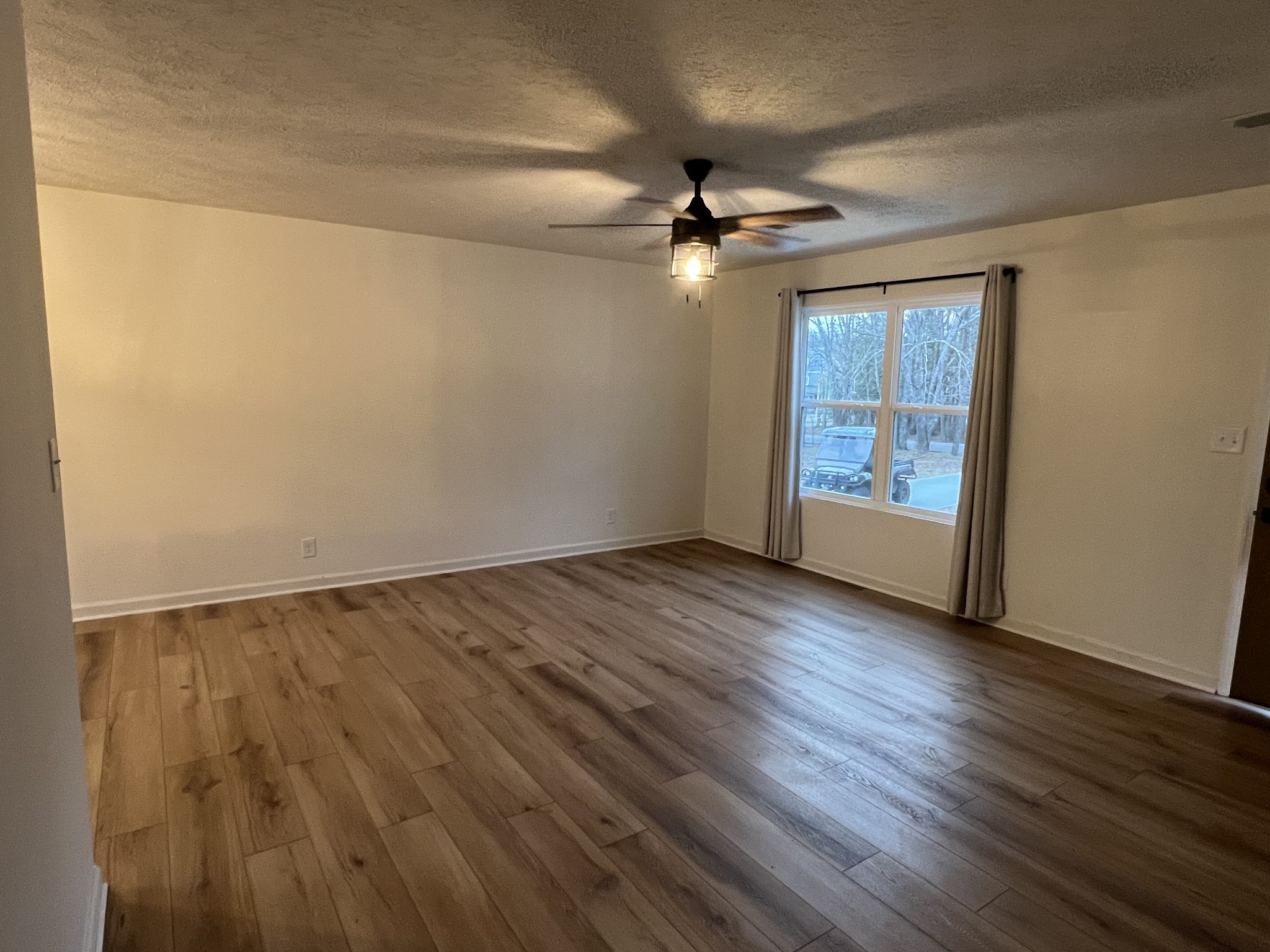 1343 Oaklawn Road Chapmansboro, TN 37035 - Photo 9 of 10 an empty room with wooden floor chandelier fan and windows