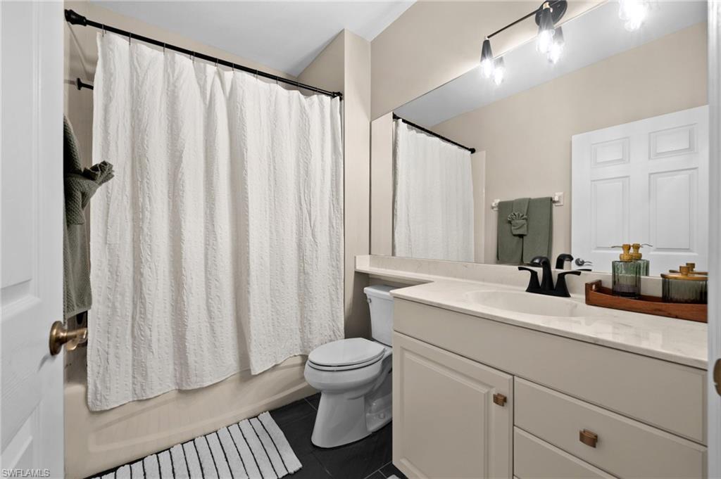 6080 Pinnacle Lane, Unit 1701 Naples, FL 34110 - Photo 28 of 39 a bathroom with a sink a toilet and shower curtain