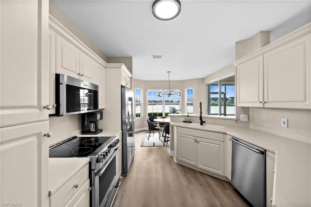 6080 Pinnacle Lane, Unit 1701 Naples, FL 34110 - Photo 6 of 39 a kitchen with stainless steel appliances a stove sink microwave and cabinets