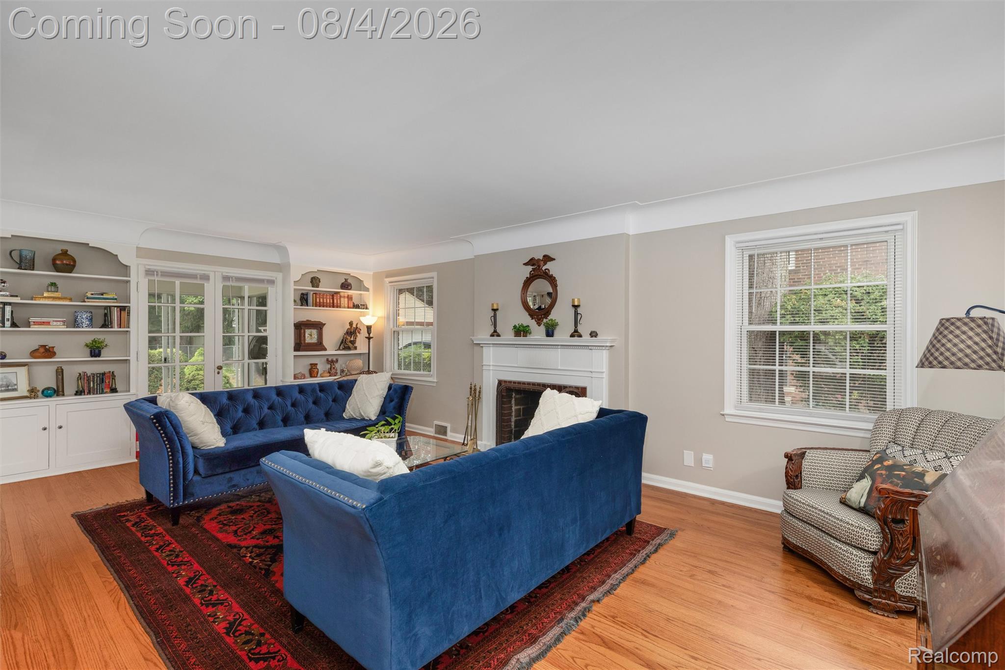 1729 Broadstone Road Grosse Pointe, MI 48236 - Photo 7 of 39 Bright living area featuring wood-finish flooring, a white mantel fireplace, and built-in shelving with lower cabinetry