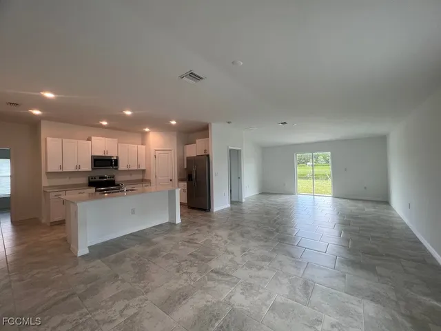 a view of kitchen with kitchen island granite countertop a stove top oven a sink a counter top space and cabinets