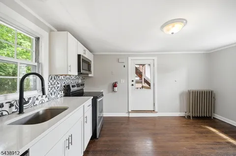 a kitchen with stainless steel appliances granite countertop a sink a stove and a refrigerator with wooden floor