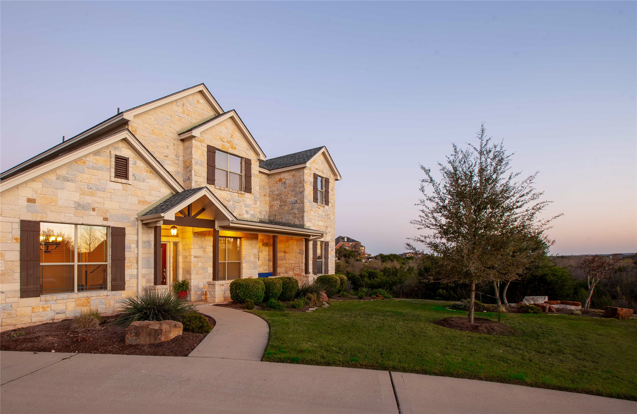 1432 Tom Sawyer Road Austin, TX 78737 - Photo 33 of 33 A welcoming stone facade home with an inviting front porch and manicured landscaping offers serene curb appeal.