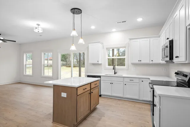 a large kitchen with kitchen island a large counter top space a sink stainless steel appliances and cabinets