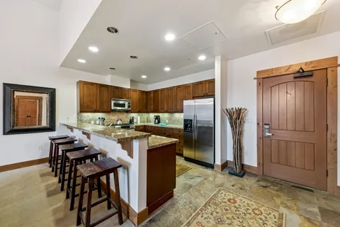 a kitchen with stainless steel appliances kitchen island granite countertop a refrigerator and a stove top oven