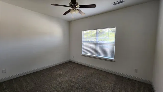 an empty room with a window and a fan