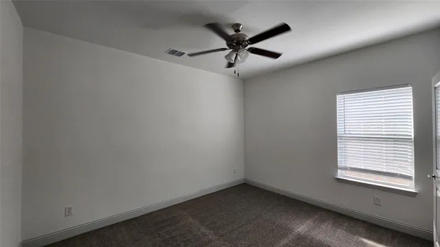 an empty room with a window and a fan