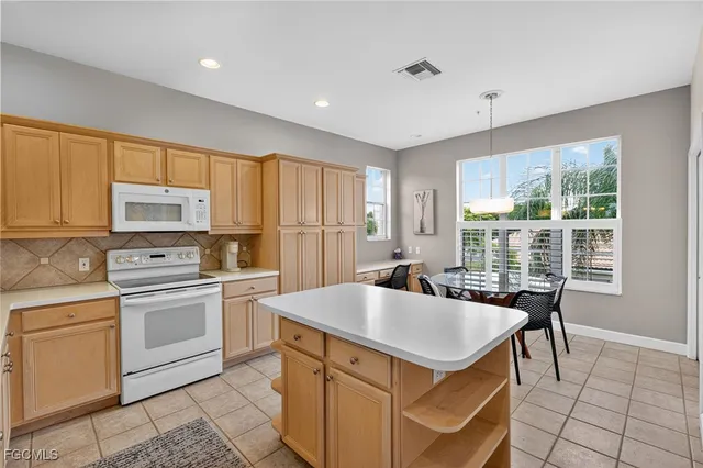 a kitchen with kitchen island a stove a sink a refrigerator and white cabinets with wooden floor