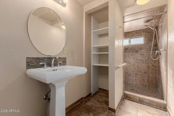 a bathroom with a sink a mirror a glass door and shower
