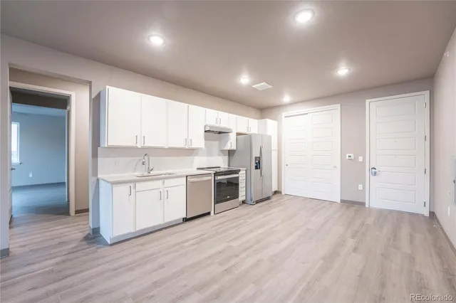 a large white kitchen with a sink and stainless steel appliances
