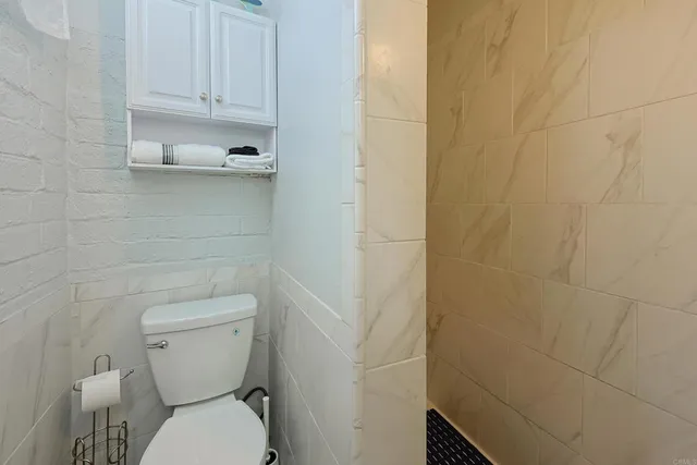 a white toilet sitting next to a white wall