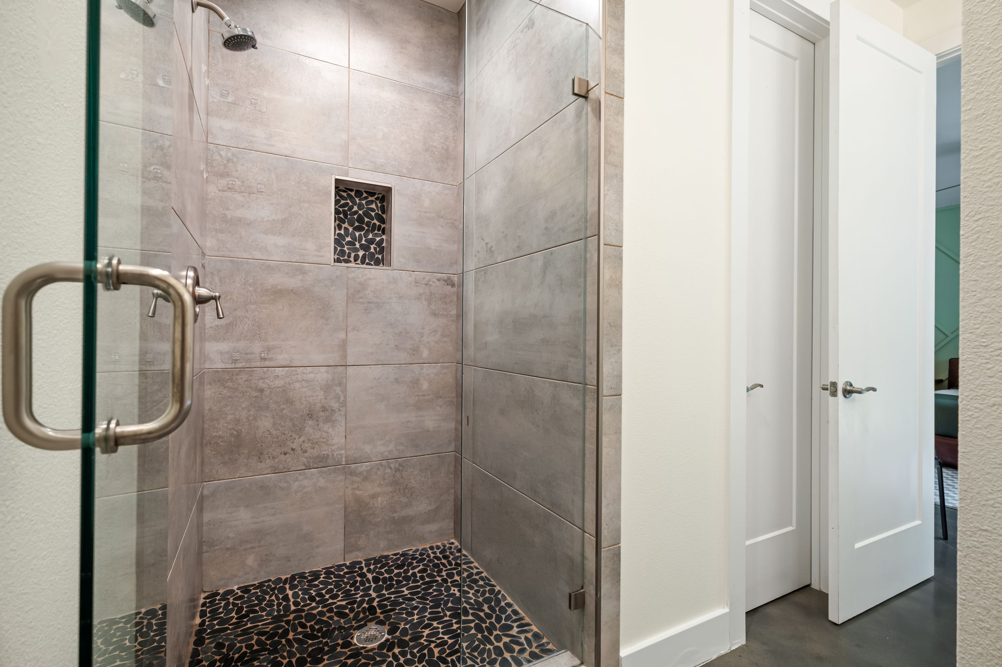 1902 Webberville Road, Unit B Austin, TX 78721 - Photo 21 of 39 A stylish, naturally illuminated shower with textured tile walls and a contrasting pebble floor.