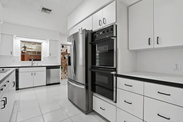 a kitchen with stainless steel appliances a refrigerator sink and cabinets