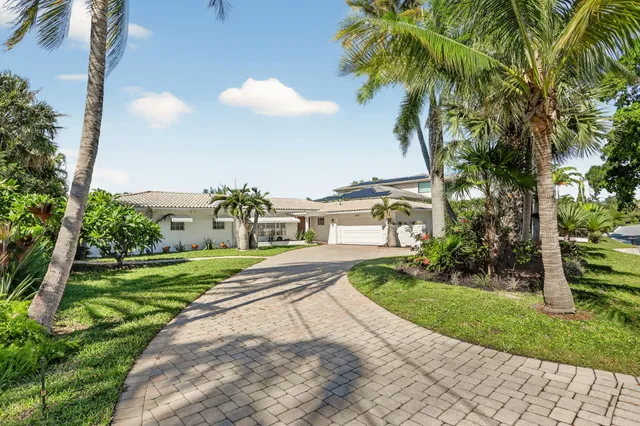 a view of a white house with a big yard and potted plants