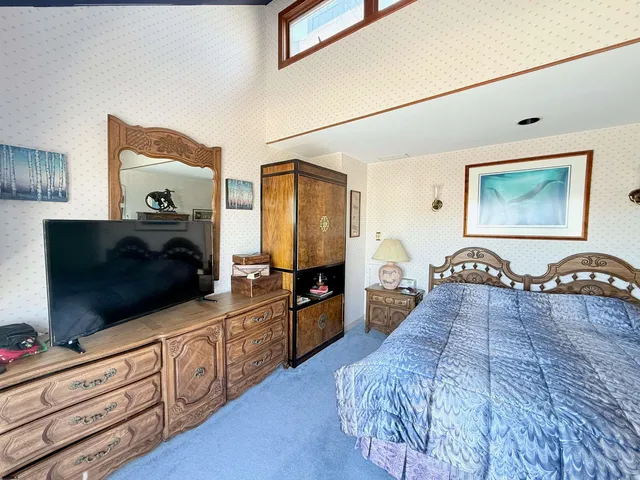 a large bedroom with a bed and a flat tv screen on dresser