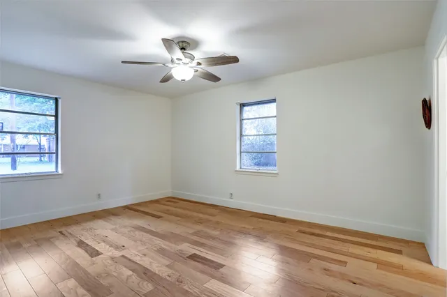 a view of empty room with wooden floor and fan