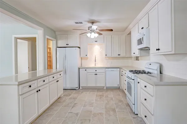 a kitchen with white cabinets and white appliances