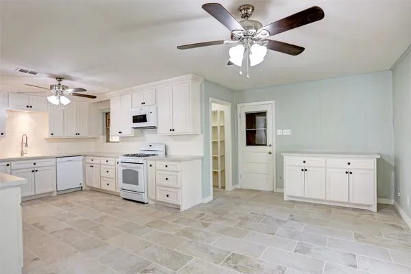 a large white kitchen with cabinets