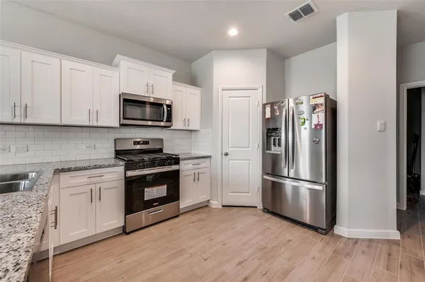 a kitchen with stainless steel appliances and wooden floor