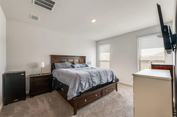 a bedroom with a bed and a flat tv screen on dresser