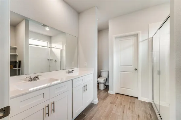 a spacious bathroom with a double vanity sink a mirror and a toilet
