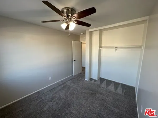 an empty room with closet and a chandelier fan