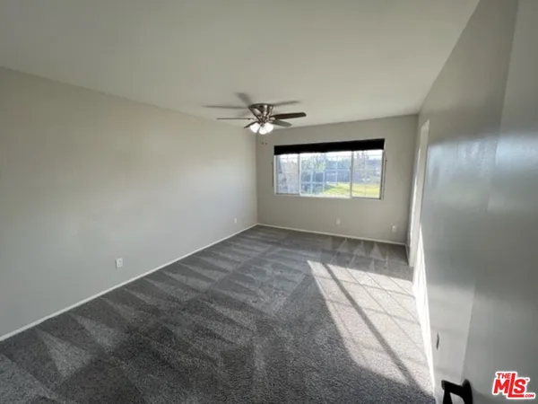 an empty room with windows and ceiling fan