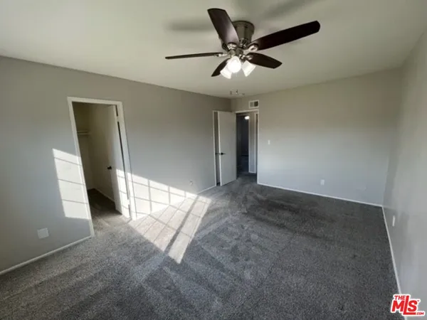 an empty room with a ceiling fan and window