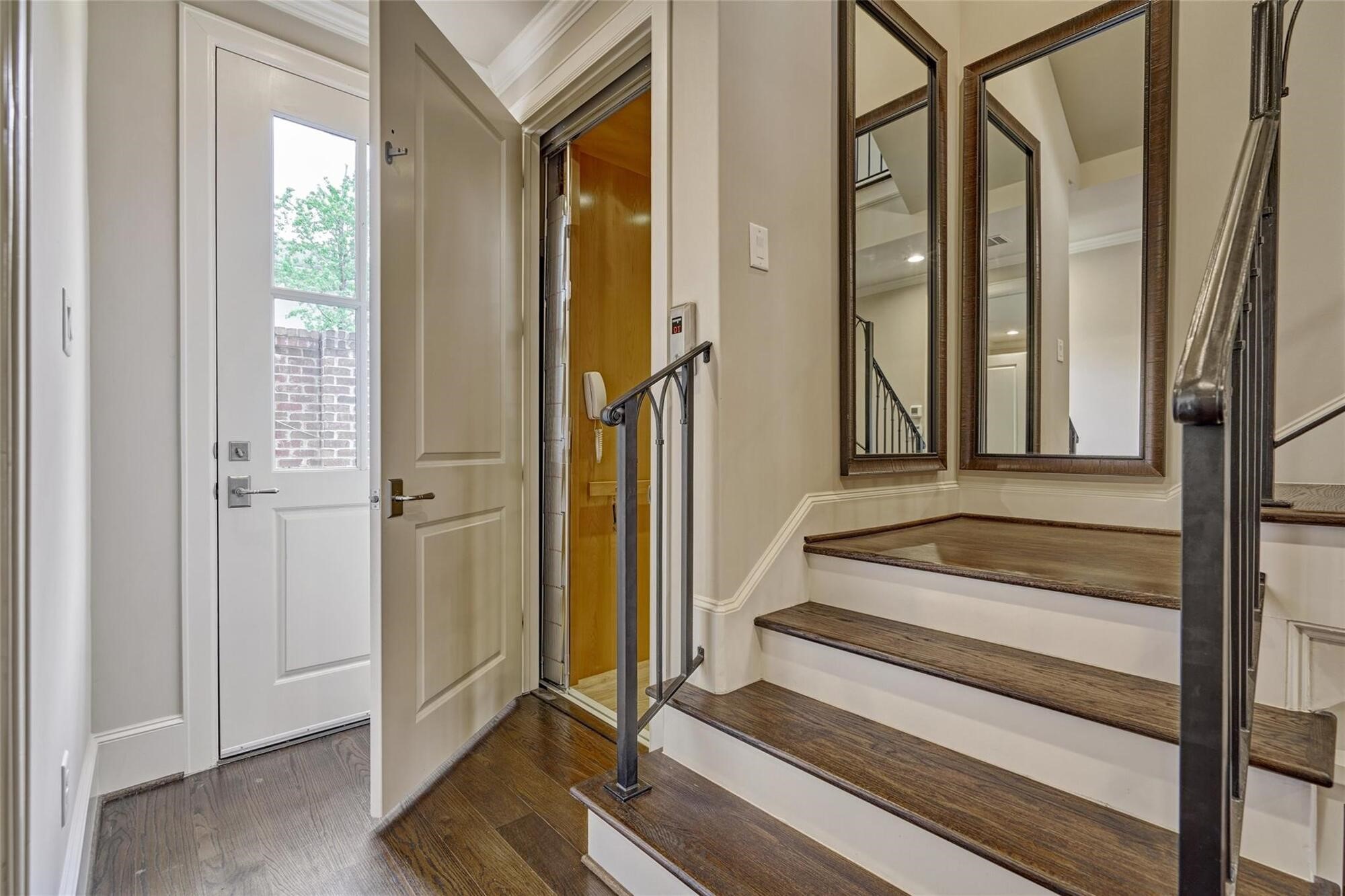 122 Gateway Park Place Spring, TX 77380 - Photo 7 of 44 Elevator access beside the staircase, with upgraded wood flooring and a bright rear entry door.
