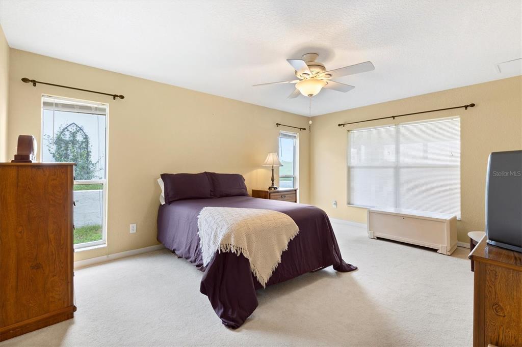 17083 Southeast 115th Terrace Road Summerfield, FL 34491 - Photo 19 of 43 a spacious bedroom with a bed and a chandelier