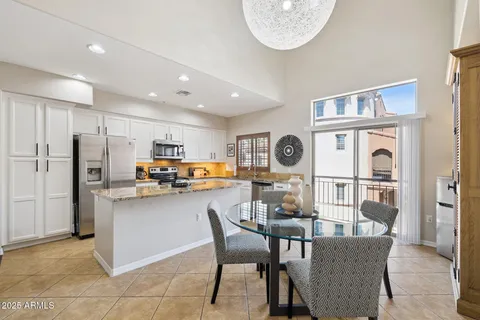 a kitchen with stainless steel appliances a dining table chairs and a refrigerator