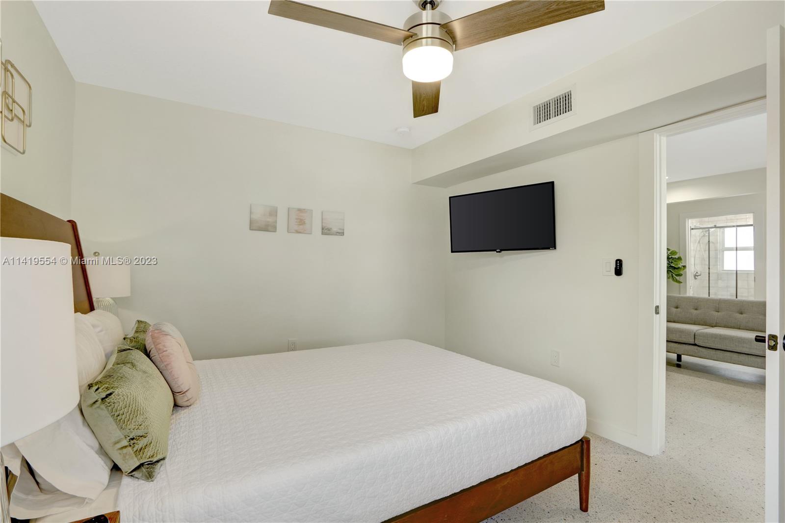 Palm Trail Delray Beach, FL 33483 - Photo 17 of 55 a bedroom with a bed and a flat tv screen on the dresser