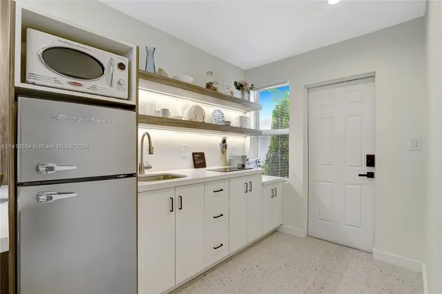 a kitchen with stainless steel appliances a dining table chairs and white cabinets