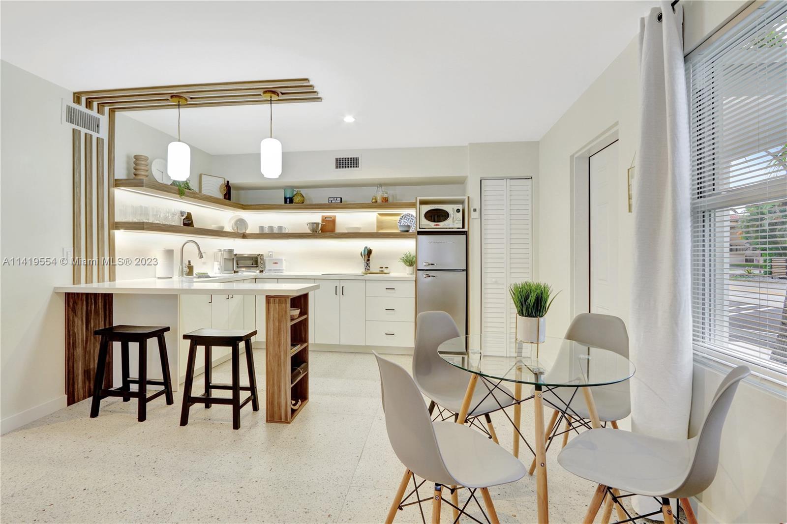 Palm Trail Delray Beach, FL 33483 - Photo 33 of 55 a kitchen with stainless steel appliances a dining table chairs and white cabinets