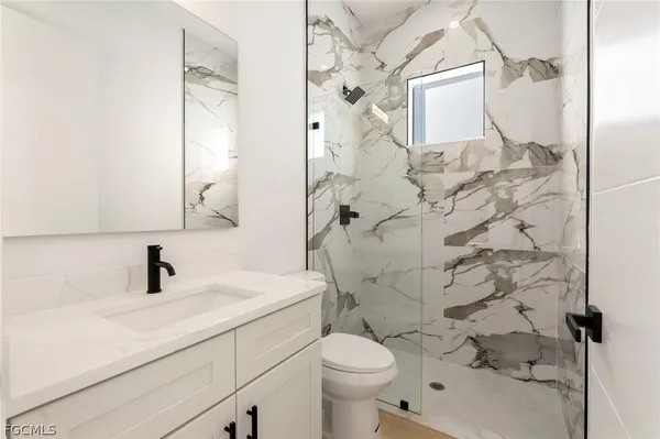 a bathroom with a sink toilet vanity and shower
