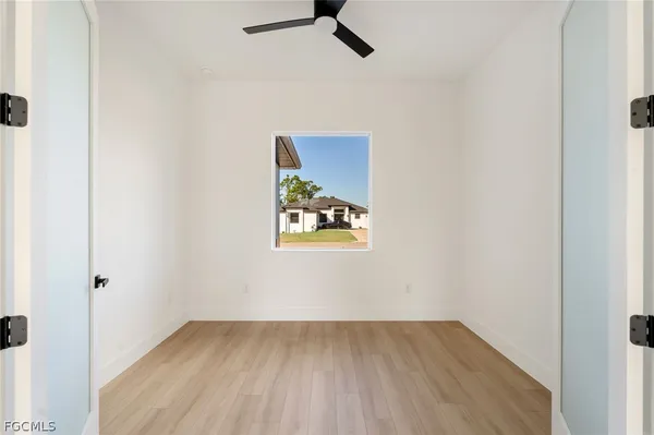 an empty room with a window and a ceiling fan