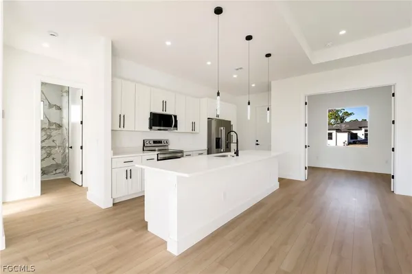 a view of kitchen with stainless steel appliances kitchen island wooden floors and white cabinets