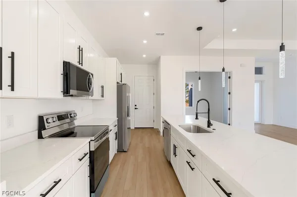 a kitchen with stainless steel appliances a sink a stove a refrigerator a center island and cabinets