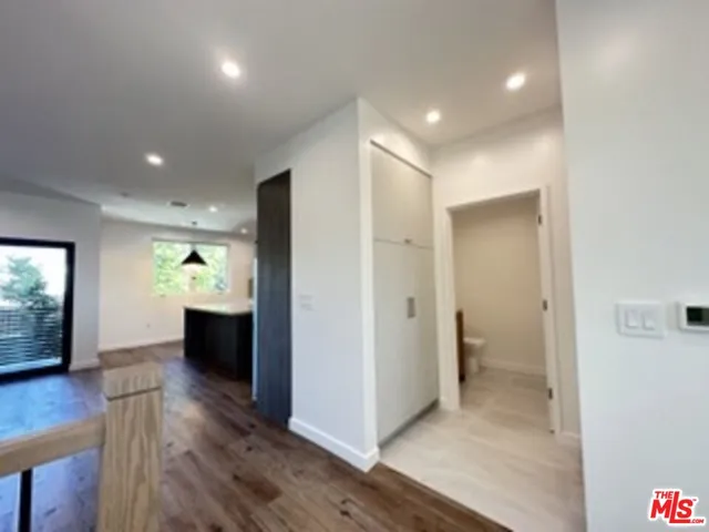 a view of a hallway with wooden floor and a bathroom
