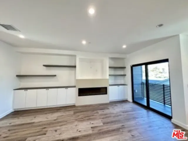 a view of empty room with wooden floor and window