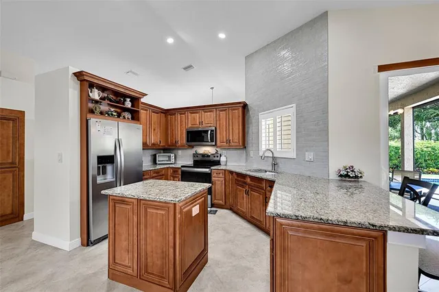a kitchen with granite countertop kitchen island stainless steel appliances a sink stove and refrigerator
