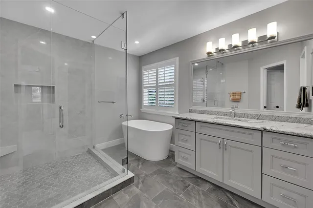 a bathroom with a granite countertop sink a toilet a mirror and shower