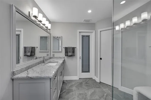 a bathroom with a granite countertop sink a refrigerator and a mirror