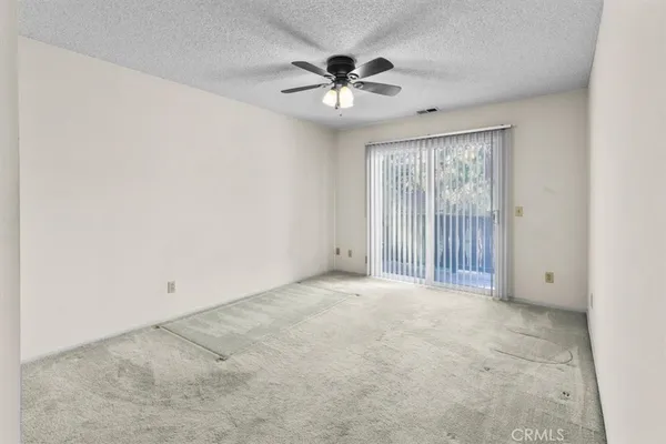 an empty room with chandelier fan and windows