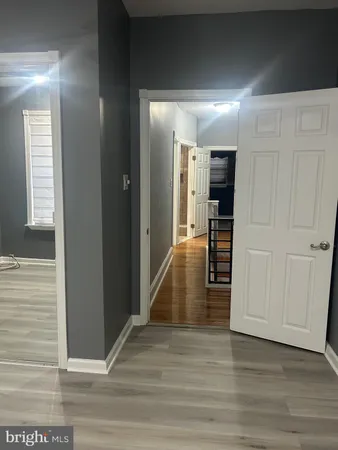 a view of a hallway with wooden floor staircase and a living room