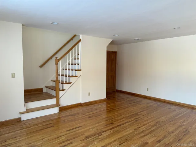 a view of an empty room with wooden floor and stairs