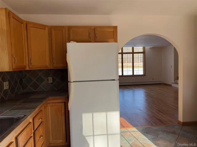 a view of a kitchen with a fridge and wooden floor