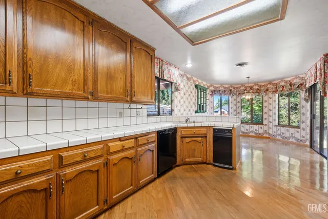 a dining hall with stainless steel appliances granite countertop a refrigerator a sink dishwasher and wooden cabinets with wooden floor